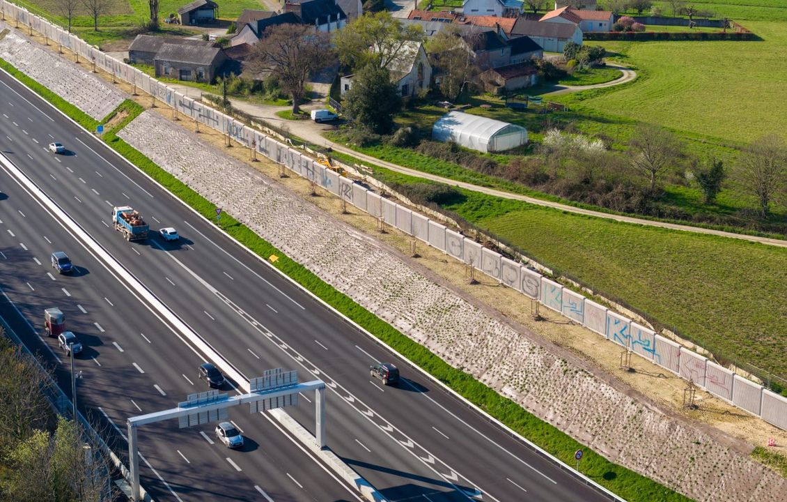 Photo vue du ciel de l'autoroute A11. Des maisons se trouvent aux abords de l'autoroute, et des murs acoustiques se dressent entre les deux pour protéger les riverains des nuisances sonores.
